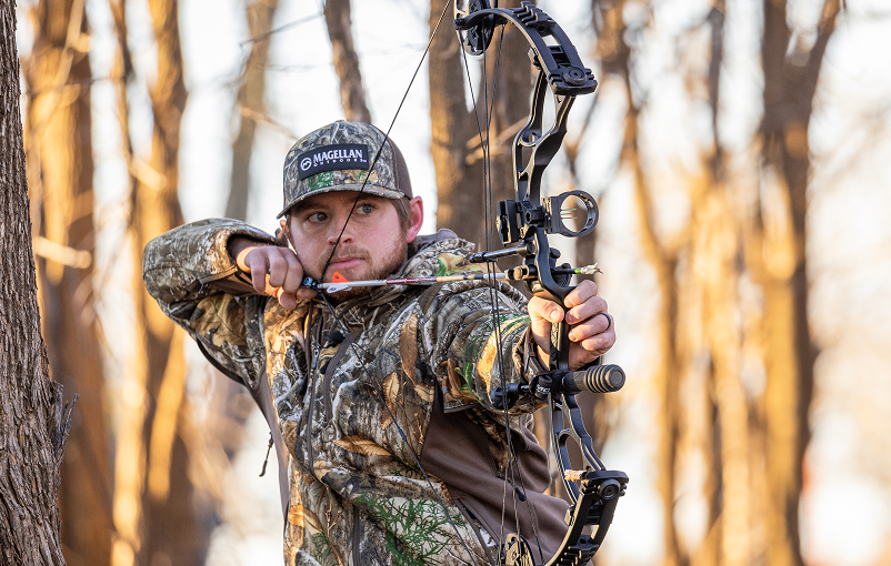 Un chasseur à l'arc habillé en camouflage, prêt à tirer